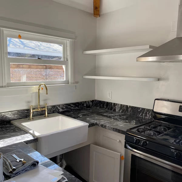 Kitchen with white sink, black stove, and marble-like countertop.