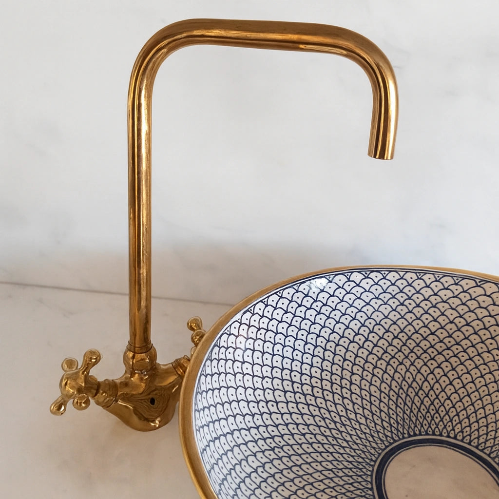 Brassfaucet with a decorative sink on a light background