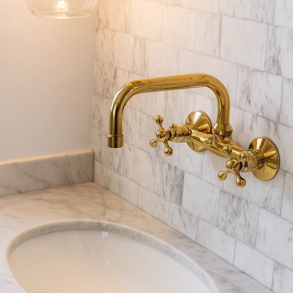 Gold faucet on a marble sink with tiled wall