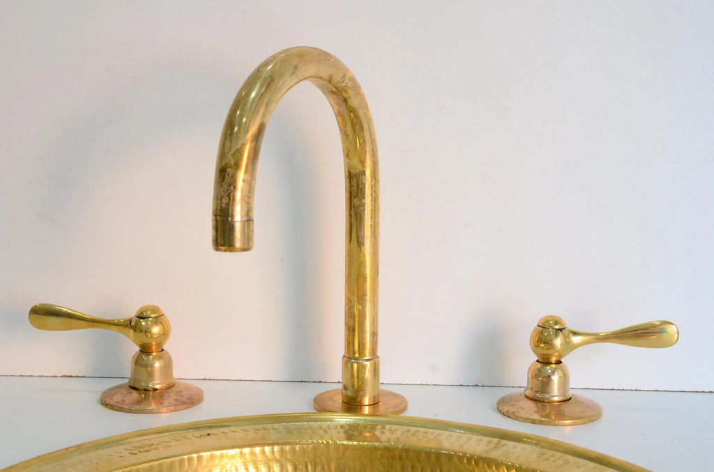 Gold faucet and handles on a sink against a white background
